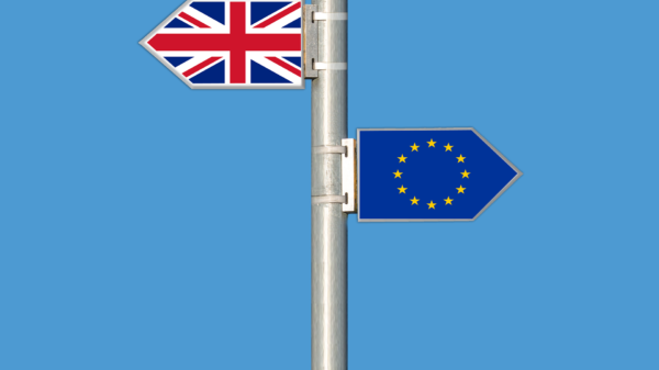 Das Foto zeigt zwei Straßenschilder, die mit der britischen Flagge und der EU-Flagge bemalt sind und in entgegengesetzte Richtungen zeigen.